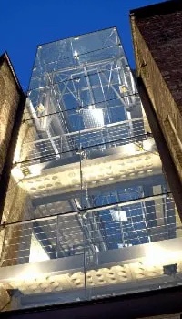 The glass tower of the i6 building lit up at night