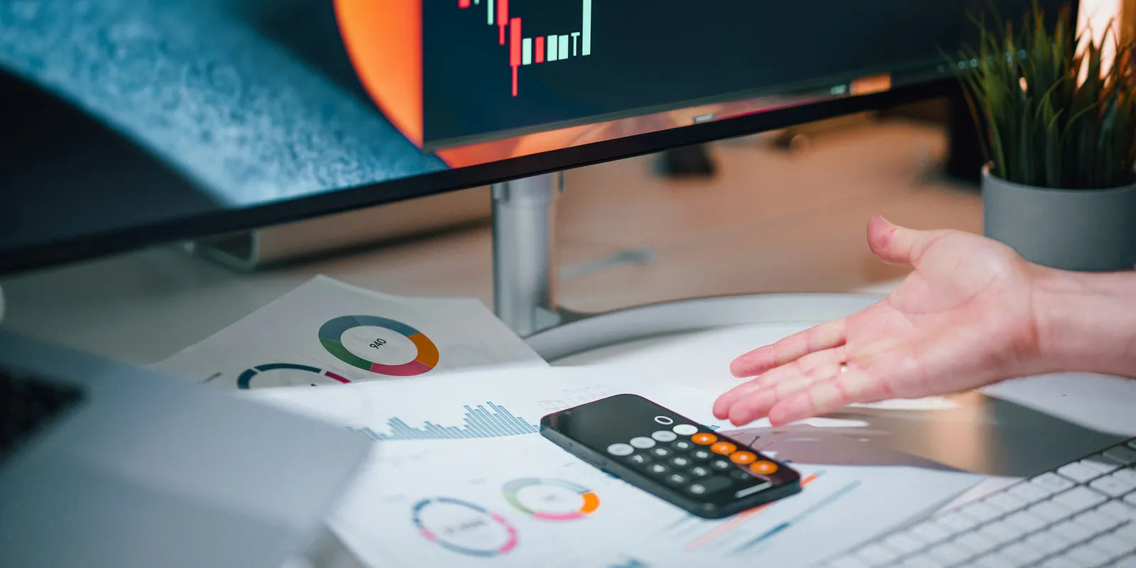 Financial charts, a calculator and a monitor on a finance team's desk