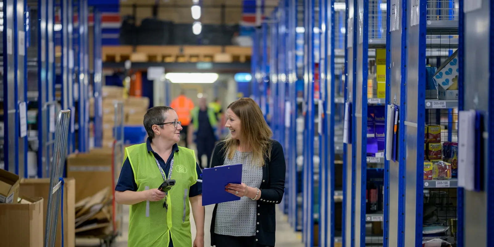 Warehouse staff checking stock levels with a scanner and clipboard