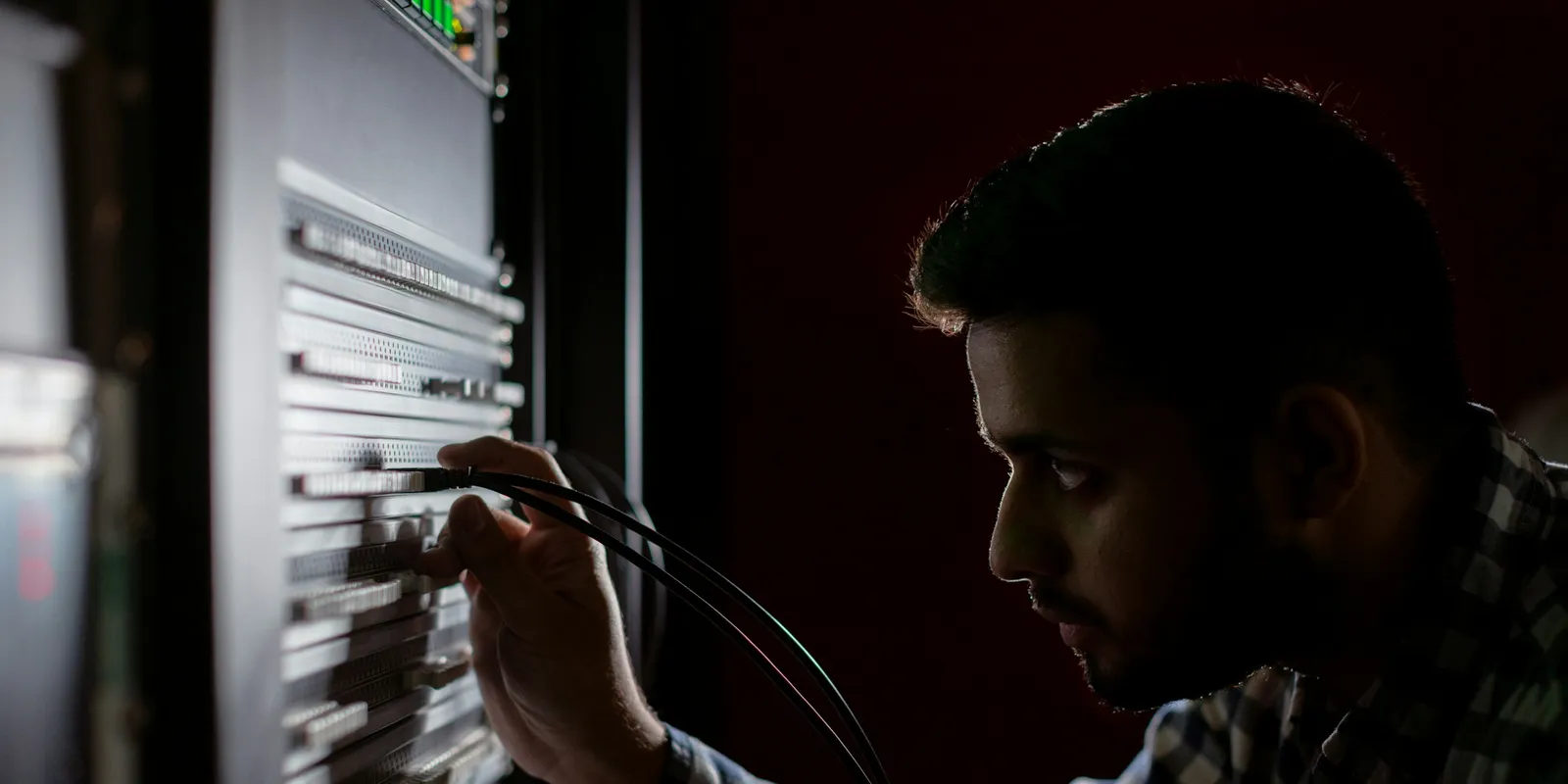 IT technician connecting cables in a network rack